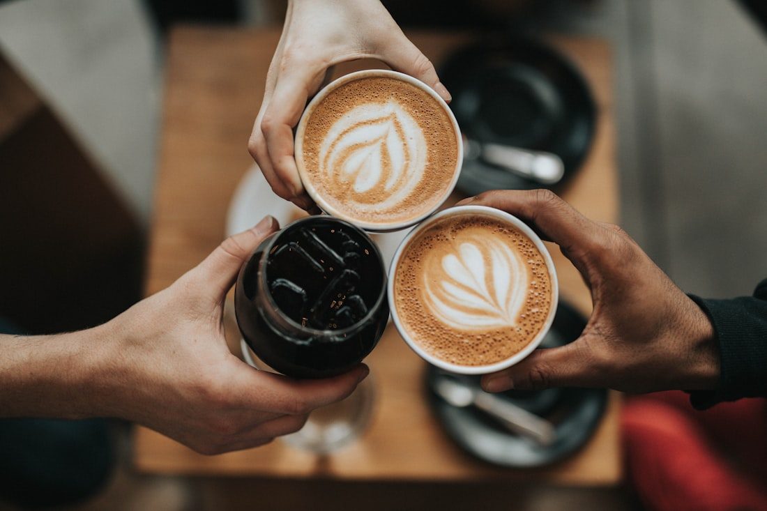 Drei Kaffeegetränke werden angestoßen